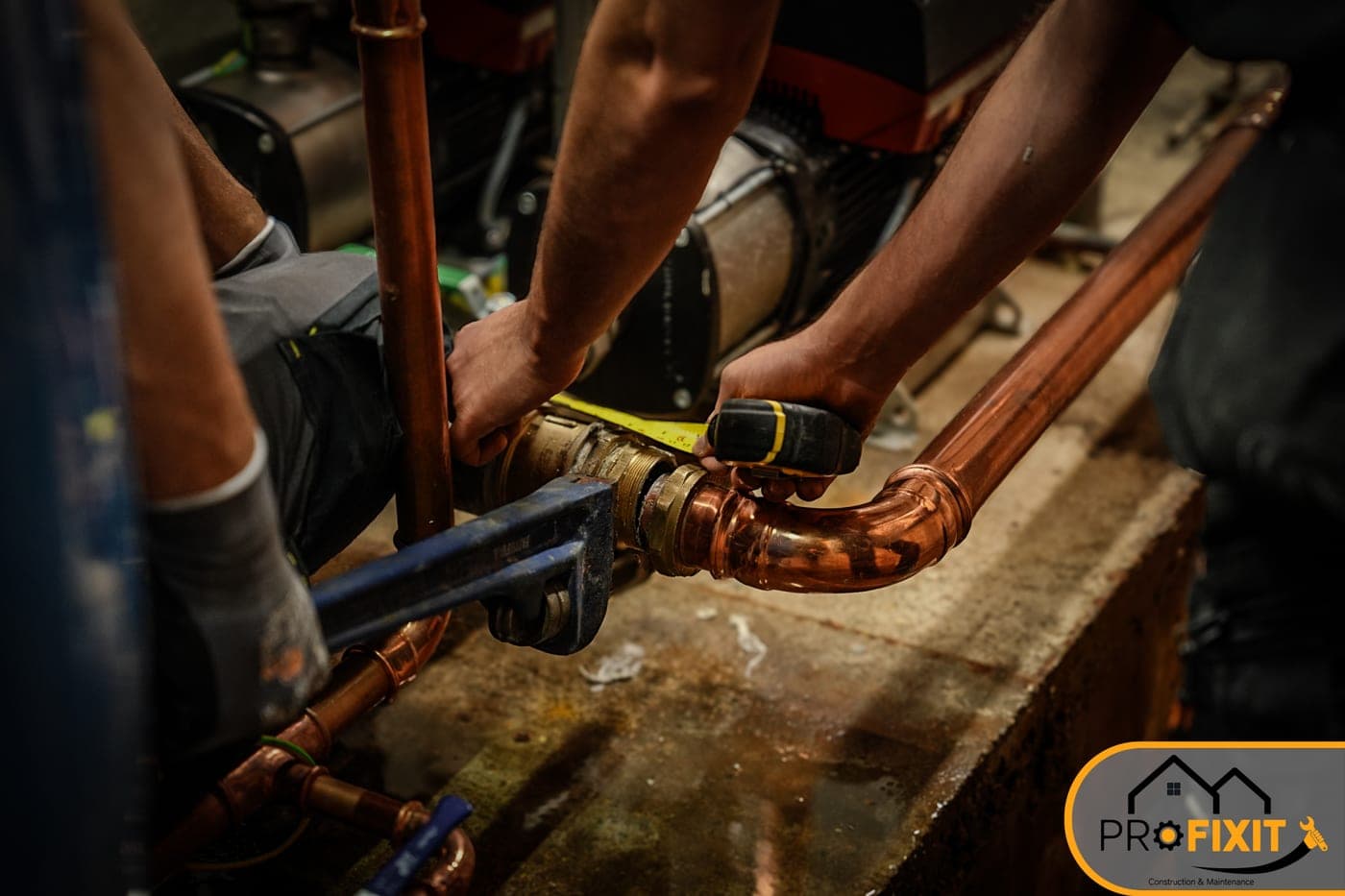 Two workers measuring and fitting copper pipe.