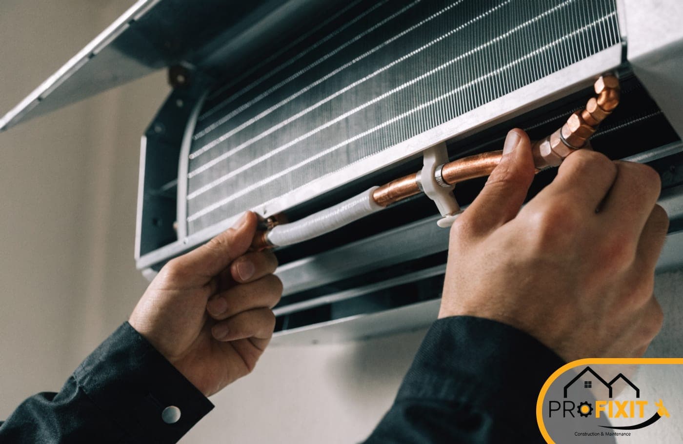 Hands fitting insulated copper pipework inside an opened wall-mounted air-conditioning unit.