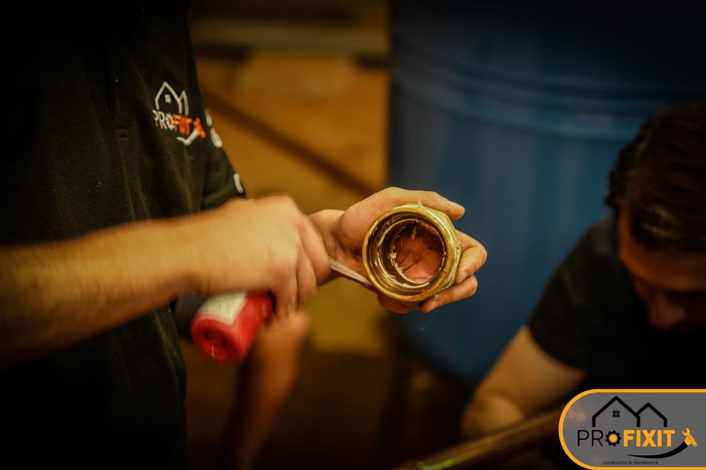 A worker holding a pipe fitting beside copper pipework.